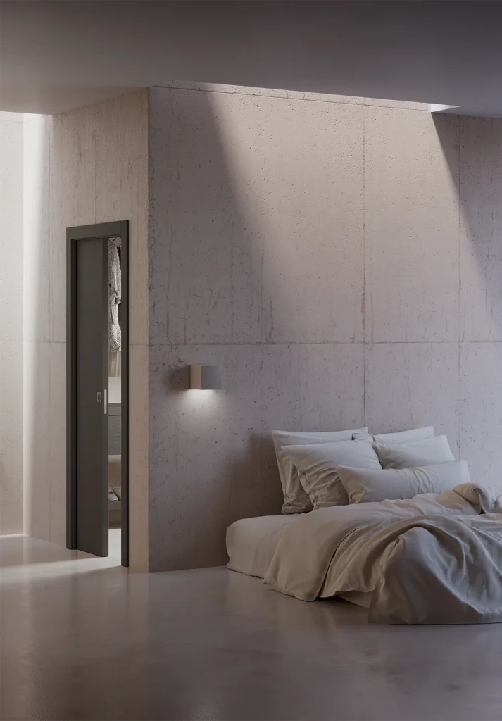 Porta della collezione Zero Phantos scorrevole interno muro, Soft antracite, inserita all'interno di una stanza materica dai toni neutri