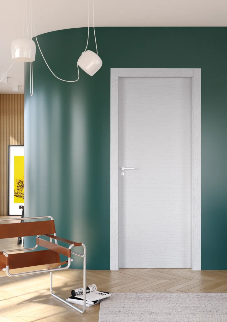 Porta battente laminato Frassino Bianco, ambientata in casa anni '70 con muro verde e poltrona color cuoio