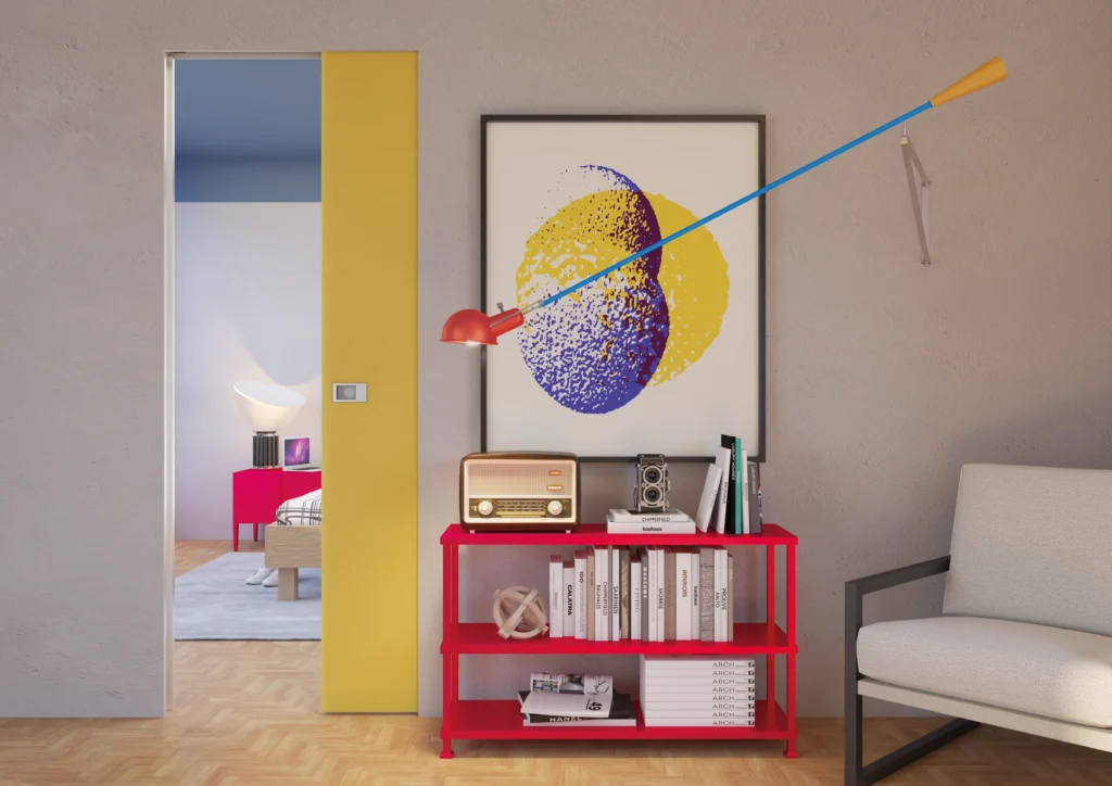 Porta interna scorrevole a scomparsa Raso Muro, laccato giallo, separa soggiorno e camera da letto, ambiente con libreria rossa.