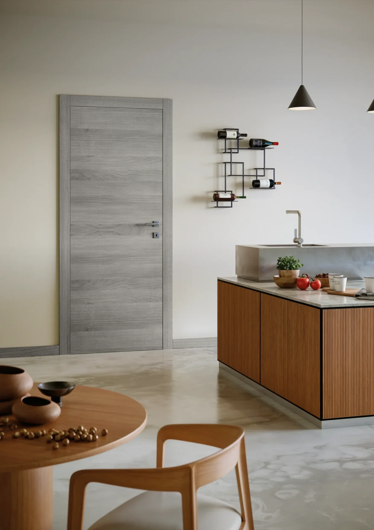 Collezione: Zero, Modello: 66L, Finitura: Olmo Grigio, Maniglia: Ellesse Cromat Porta della collezione Zero in finitura laminato Olmo Gigio, con venature tendenti al grigio, inserita all'interno di una cucina con isola centrale in legno chiaro. L'ambiente risulta molto confortevole